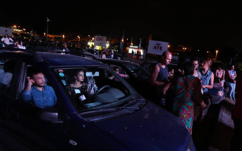 People watch a film on the first day of screening at a drive-in open air cinema at the Municipal car park of Sidi Bou Said.