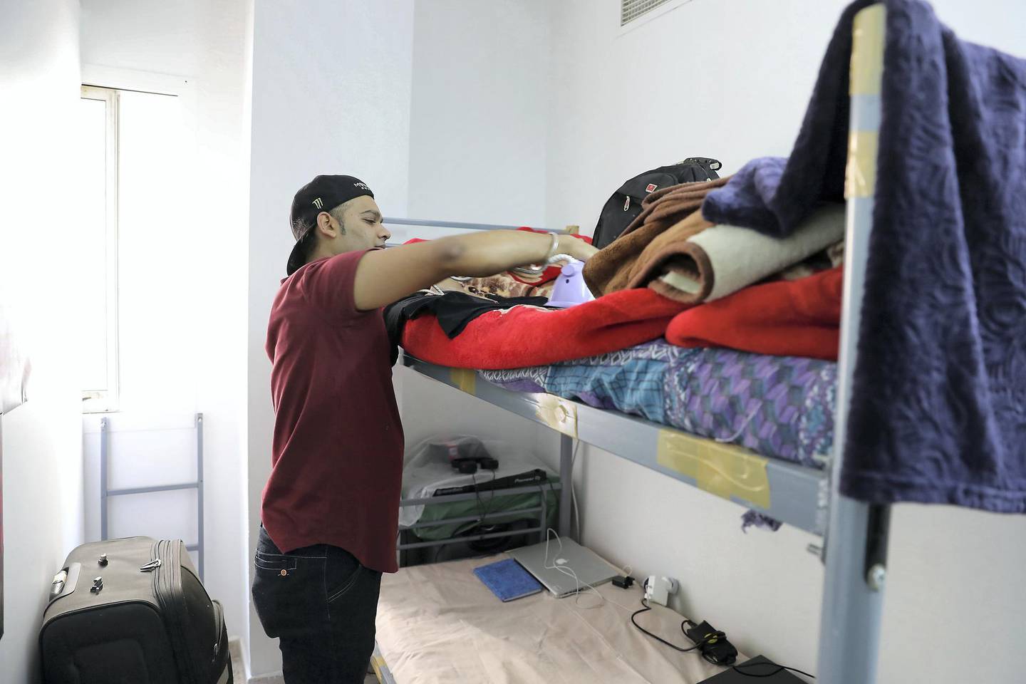 DUBAI , UNITED ARAB EMIRATES , March 13 – 2019 :- Vishal Shahid , Sikh from Pakistan doing ironing to get ready for work at his sharing accommodation in Bur Dubai area in Dubai. He is working as a waiter at the players lounge at the Country Club hotel in Bur Dubai but wanted to become DJ, Rapper, Dancer and Writer.  ( Pawan Singh / The National ) For Photo Feature. Story by Pawan Singh