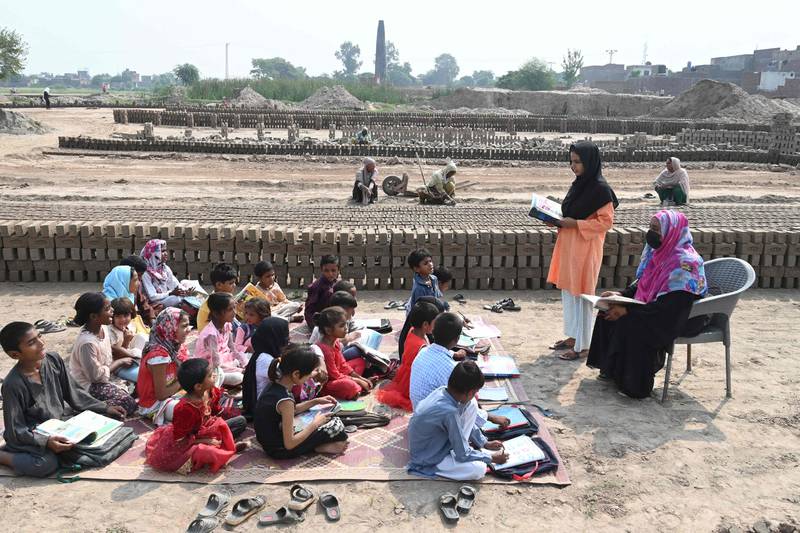 Children of brick kiln workers attend a class at a brick kiln site in Lahore. AFP
