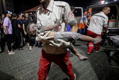 A Palestine Red Crescent Society paramedic carries a wounded child to Al Shifa hospital in Gaza city, following an Israeli air strike. EPA