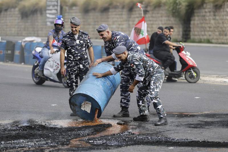 Lebanese security forces empty barrels used by protesters to block the main Beirut-Tripoli highway, near Nahr al-Kalb north of Lebanon's capital, during ongoing anti-government demonstrations. AFP