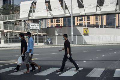 DUBAI, UNITED ARAB EMIRATES. 08 APRIL 2020. Three men wearing face masks and gloves as per Government order walk across a street in Jumeirah Lake Towers. (Photo: Antonie Robertson/The National) Journalist: Standalone. Section: National.