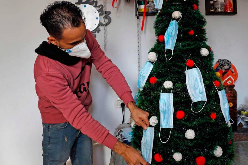 Palestinian artist Wissam Farhat decorates a Christmas tree with protective masks in Gaza City. AFP