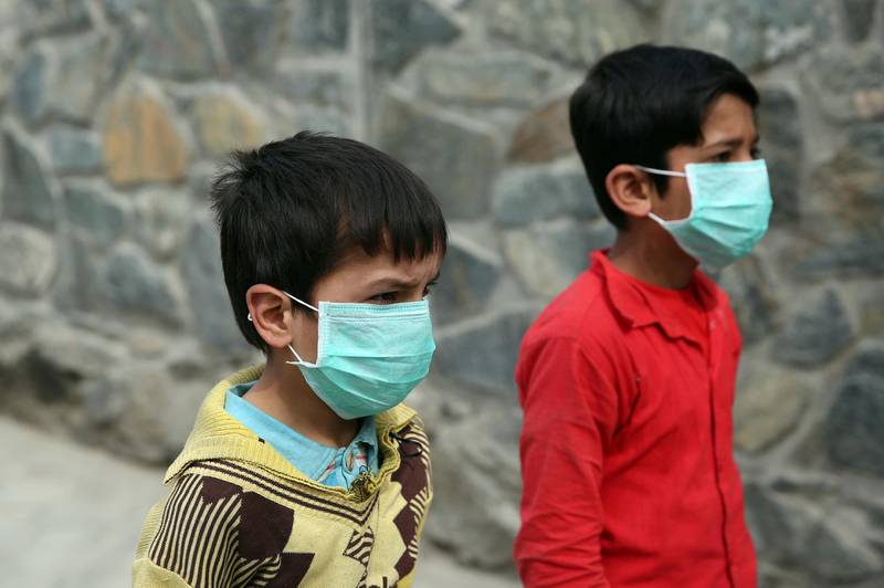 Afghan boys wearing face masks walk at a down town street in Kabul, Afghanistan. AP Photo