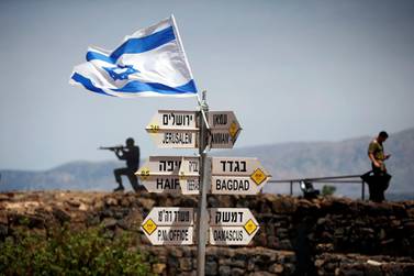 An Israeli soldier stands next to signs pointing out distances to different cities, on Mount Bental, an observation post in the Israeli-occupied Golan Heights . Reuters/Ronen Zvulun