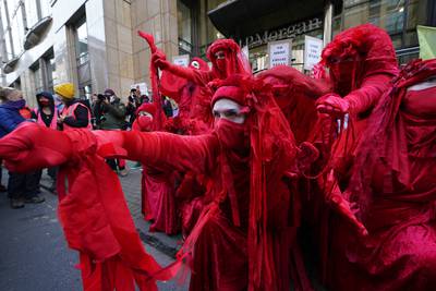 Climate activists from the Red Rebel Brigade take part in a protest outside the offices of JP Morgan on Waterloo Street, Glasgow. PA