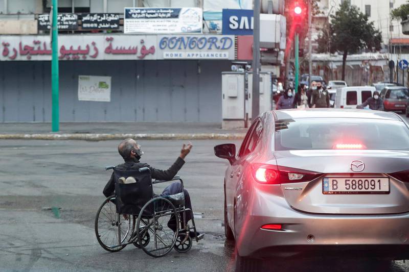 A wheelchair-bound beggar is seen next to a car stopping at a red light, in Lebanon's capital Beirut, despite a total lockdown due to the COVID-19 coronavirus pandemic.  AFP