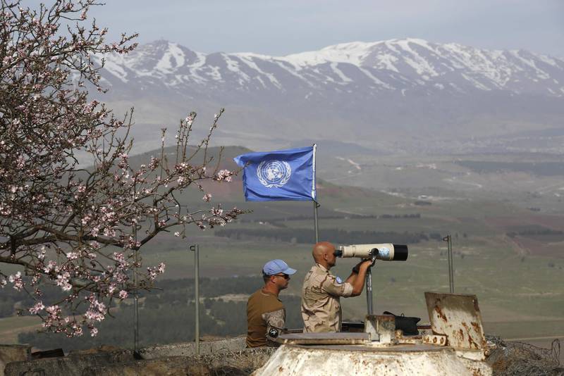 TOPSHOT - UN members look through binoculars as they monitor the Israel-Syria border in the Israeli-annexed Golan Heights, on February 10, 2018.
Israel struck a dozen Syrian and Iranian targets inside Syria in "large-scale" raids after an Israeli fighter jet crashed under fire from Syrian air defences in a severe increase in tensions, the military said. / AFP PHOTO / JALAA MAREY