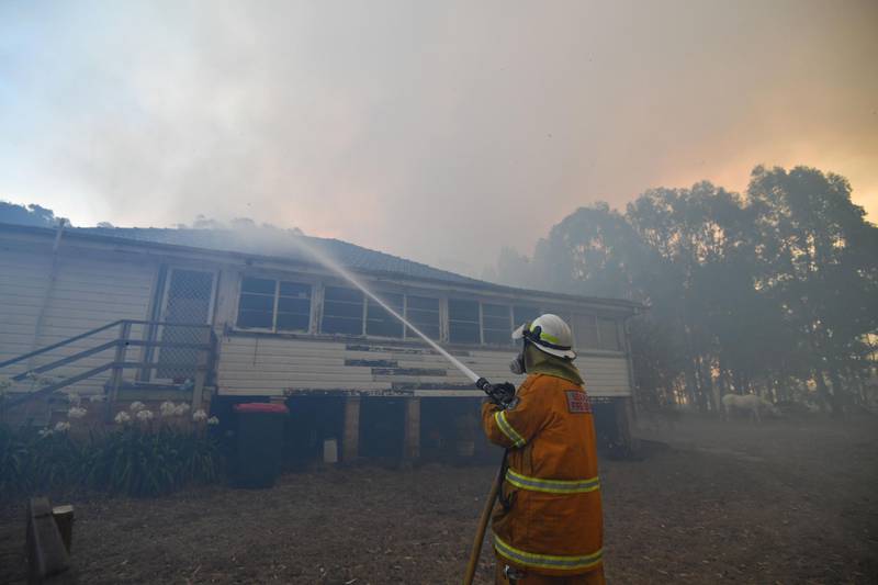 A firefighter hoses down property in the hope of saving it from nearby bushfires around the town of Nowra. AFP