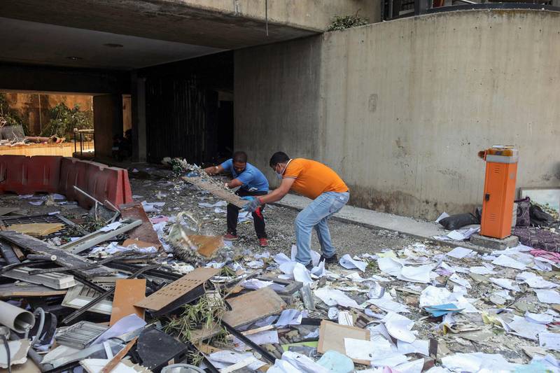 People help clear rubble and debris from the driveway of a residential building in Beirut. Bloomberg