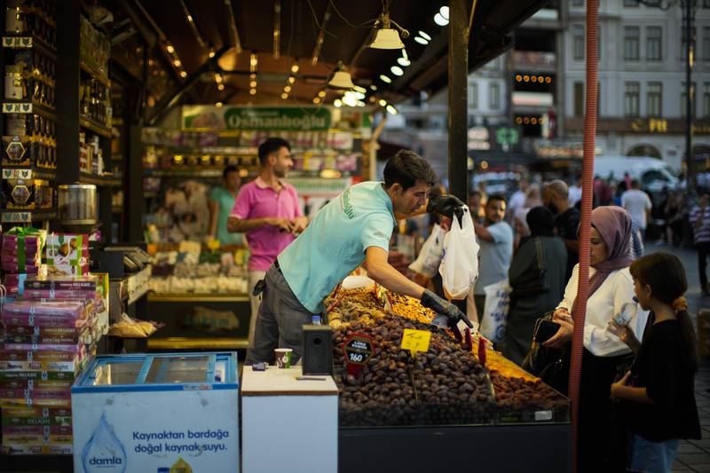 A merchant talks to a customer at the Egyptian spices market in Istanbul. Turkey's central bank on Thursday lowered its key interest rate despite inflation surging to nearly 80 per cent. AP