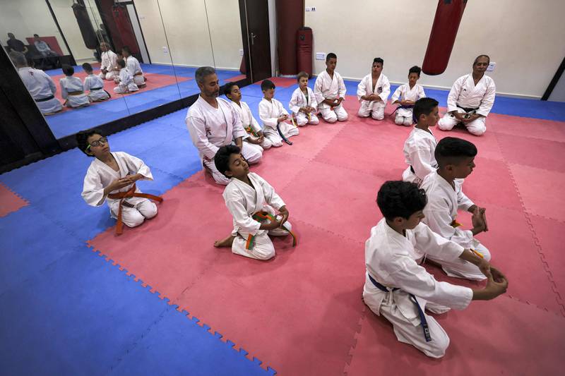 Karate students kneel while doing breathing exercises.