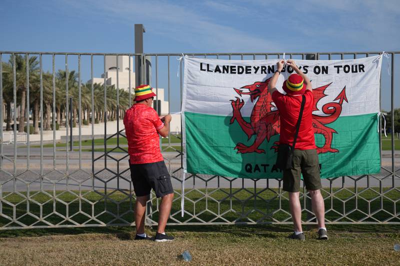 Wales fans attach their country's flag to railings at the Corniche Walk Way Park. PA