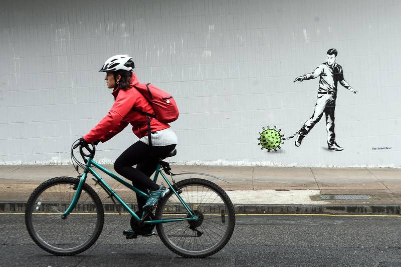 A cyclist passes a Coronavirus-inspired piece of graffiti in Glasgow as life in Britain continues during the nationwide lockdown to combat the novel coronavirus pandemic.   AFP
