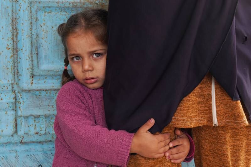 A Syrian girl holds on to her mother.