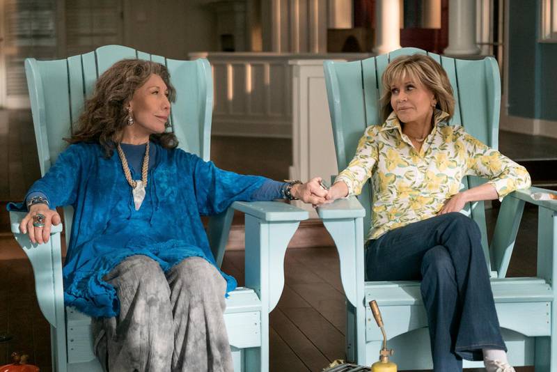 This image released by Netflix shows Lily Tomlin, left, and Jane Fonda in a scene from the comedy series "Grace And Frankie." As the fifth-season adventures of "Grace and Frankie" begin, viewers can rest assured there's more to come. Series creator Marta Kauffman and Netflix said Tuesday, Jan. 15, 2019,  that the comedy starring Fonda and Tomlin has been renewed for season six, due in 2020. (Ali Goldstein/Netflix via AP)