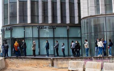 People wearing masks to protect themselves from the coronavirus pandemic wait to use ATM machines in Beirut. As the country faces a shortage of dollars, withdrawals have been cut to as little as $100 a week. AP