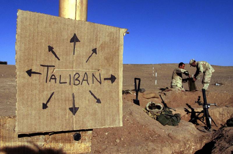 FILE PHOTO: US Marines from Charlie 1/1 of the 15th MEU (Marine Expeditionary Unit) fill sand bags around their light mortar position on the front lines of the US Marine Corps base in southern Afghanistan, December 1, 2001. Nearby a cardboard sign reminding everyone that the Taliban forces could be anywhere and everywhere. This sign is one of several at an area that Charlie Company named Camp Justice on the perimiter of the larger base. REUTERS/Jim Hollander/File Photo