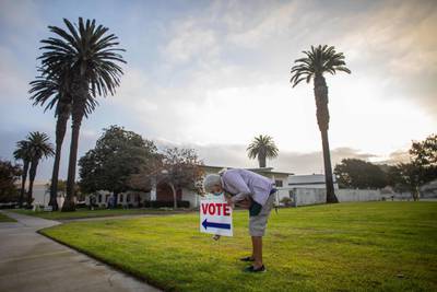 Lorraine Crawford puts vote signs as the sun rises the Main Street Branch Library vote centre in Huntington Beach, California. AFP