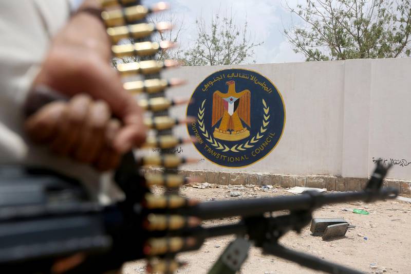 FILE PHOTO: A Yemeni government soldier holds a weapon as he stands by an emblem of the STC at the headquarters of the separatist Southern Transitional Council in Ataq, Yemen August 27, 2019. REUTERS/Ali Owidha/File Photo