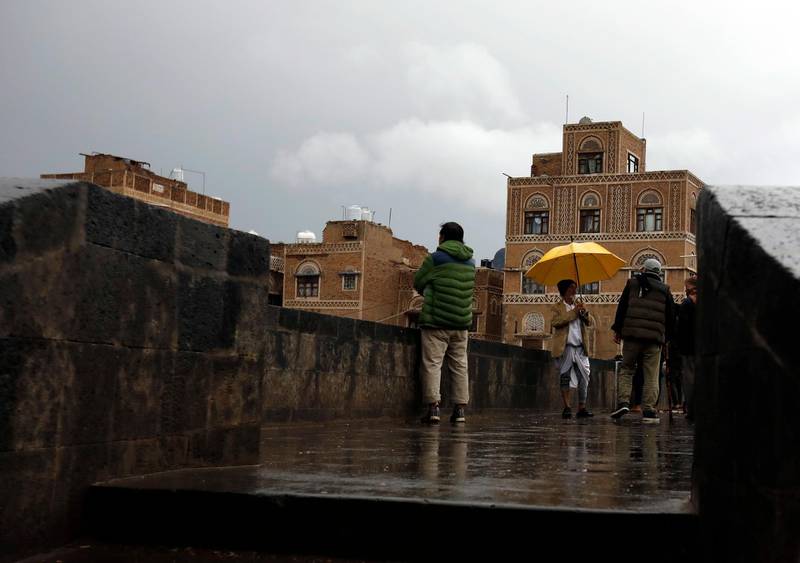 Yemenis stand on a pedestrian bridge under the rain in the old quarter of Sana'a, Yemeni.  EPA