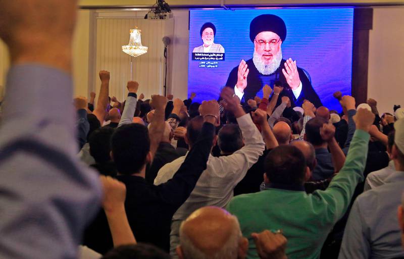 Supporters of Hassan Nasrallah, the head of Lebanon's militant Shiite Muslim Hezbollah movement, watch him speak through a giant screen at a mosque in the Lebanese capital Beirut's southern suburbs on November 1, 2019. / AFP / -
