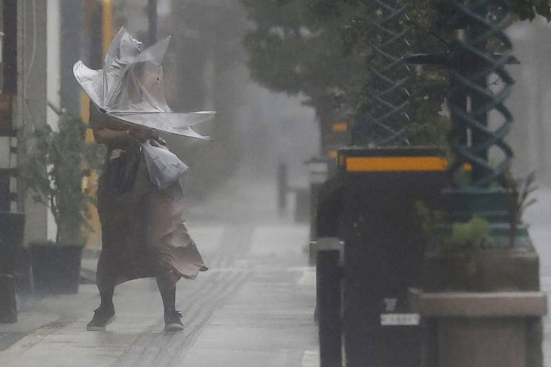 A woman makes her way through the strong wind and rain in Miyazaki, southern Japan, as Typhoon Nanmadol approaches. AP