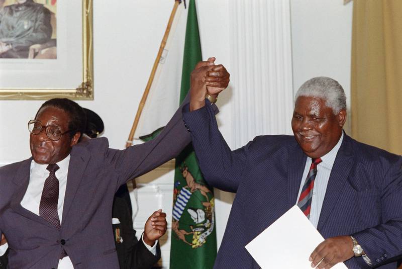 Zimbabwe's President Robert Mugabe (L) and former President of Zimbabwe African People's Union (ZAPU) Joshua Nkomo raise their fists 22 December 1987 in Nairobi. Mugabe, Zimbabwean first Premier (in 1980) and President (in 1987), was born in Kutama in 1924 (formerly Southern Rhodesia). Largely self-educated, he became a teacher. After a short periods in the National Democratic Party and ZAPU, he co-found, the Zimbabwe African National Union (ZANU). After a 10-year detention in Rhodesia (1964-74), he spent five years in Mozambique gathering support in preparation for independence in 1980.  / AFP PHOTO / ALEXANDER JOE