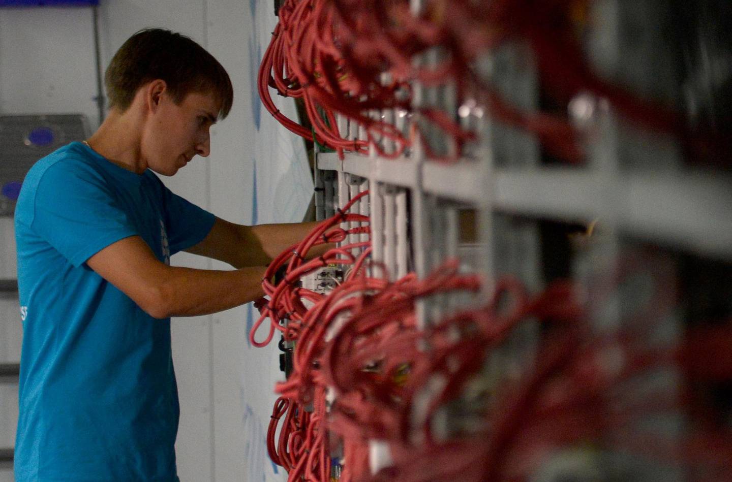 An employee inspects machines for the production of bitcoins and lightcoins at the "CryptoJuniversóe" mining centre during a presentation of the centre for the crypto currency in Kirishi on August 20, 2018. - A Russian company opened on August 20, 2018 what it said was the country's largest cryptocurrency mining unit, in a former Soviet fertilizer-producing laboratory. The opening comes as Russian authorities seek to regulate the booming cryptocurrency sector. Russia is in third place after China and the United States in the ranks of cryptocurrency-producing nations since 2015, according to a study published at the end of last year by Ernst & Young. (Photo by OLGA MALTSEVA / AFP)