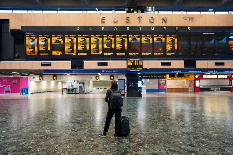 A passenger at Euston station in London looks at the departures board on the first day of a rail strike on Tuesday June 21, 2022.  Britain's biggest rail strikes in decades went ahead Tuesday after last-minute talks between a union and train companies failed to reach a settlement over pay and job security.  Up to 40,000 cleaners, signalers, maintenance workers and station staff are due to walk out for three days this week, on Tuesday, Thursday and Saturday.  (Stefan Rousseau / PA via AP)