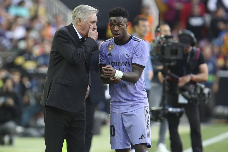 Real Madrid's head coach Carlo Ancelotti, left, speaks to Real Madrid's Vinicius Junior. Ancelotti said Vinicius did not wan tot play in initially after being targeted by racists in the crowd but that he was persuaded to carry on. AP