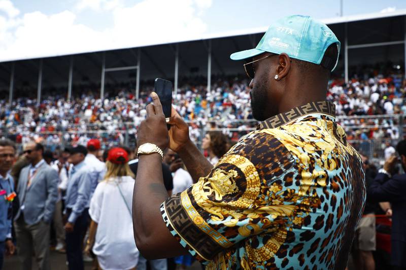 Former basketball player Dwayne Wade takes a photo on the grid during the F1 Grand Prix of Miami. Getty
