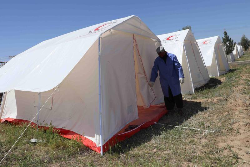 An Afghan health worker stands outside the temporary quarantine camps setup by the Red Crescent to prevent the spread of coronavirus at the entrance to the city, during a lockdown in Kandahar, Afghanistan.  EPA