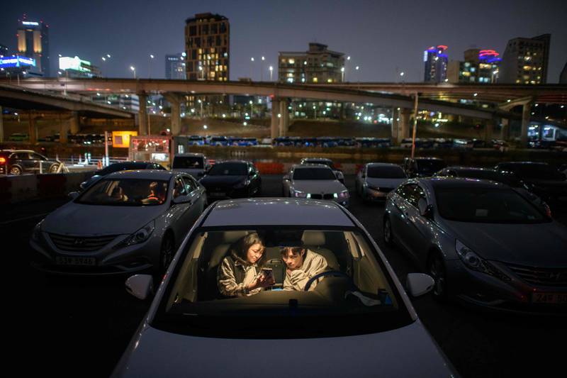 A couple look at a mobile phone as they sit in a car at a screening at a drive-through cinema in Seoul. AFP