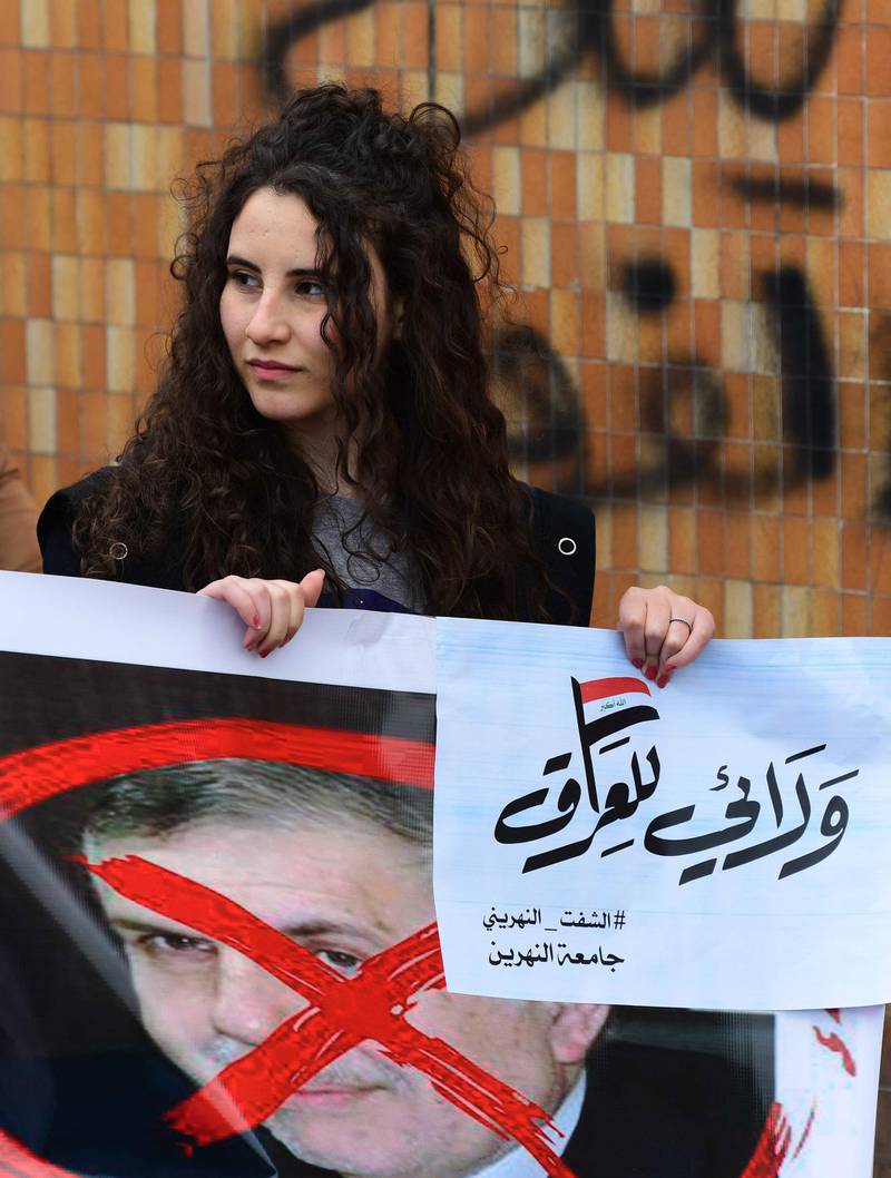 A female university student carries a crossed out picture of the newly appointed Iraqi Prime Minister Mohammed Allawi with a placards reading in Arabic 'My loyalty to Iraq', during a strike and protests in central Baghdad, Iraq.  EPA