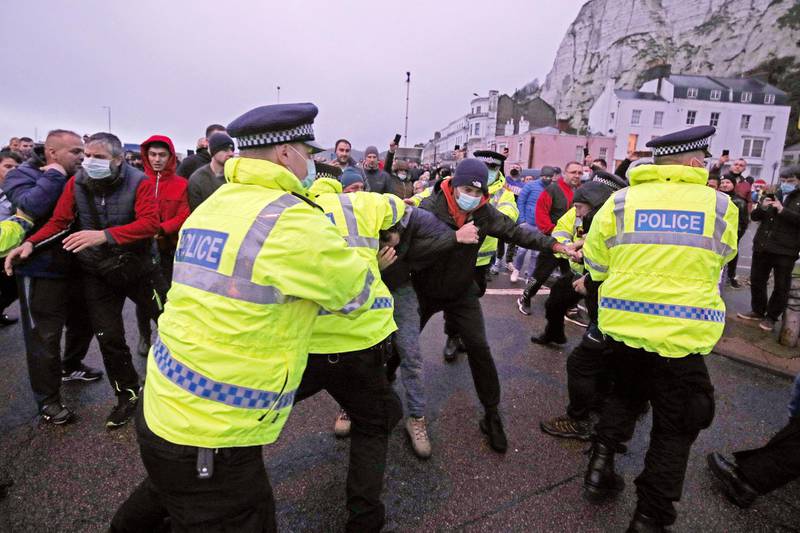 Truck drivers scuffle with police trying to hold them back at the entrance to the Port of Dover, in Kent, England. Freight from Britain and passengers with a negative virus test began arriving on French shores Wednesday, after France relaxed a two-day blockade over a new virus variant that had isolated Britain, stranded thousands of drivers and raised fears of shortages.  AP