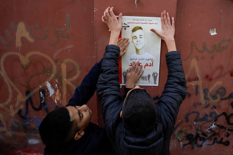 Boys put up a poster of Palestinian teenager Adam Ayyad, who medics said was killed by Israeli forces. Reuters