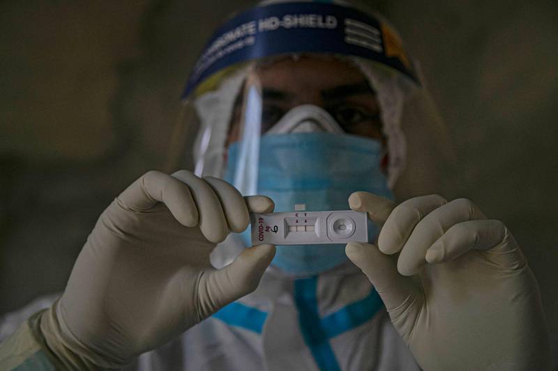 A health worker displays a test kit showing a positive result for Covid-19 in Gauhati, India. AP Photo