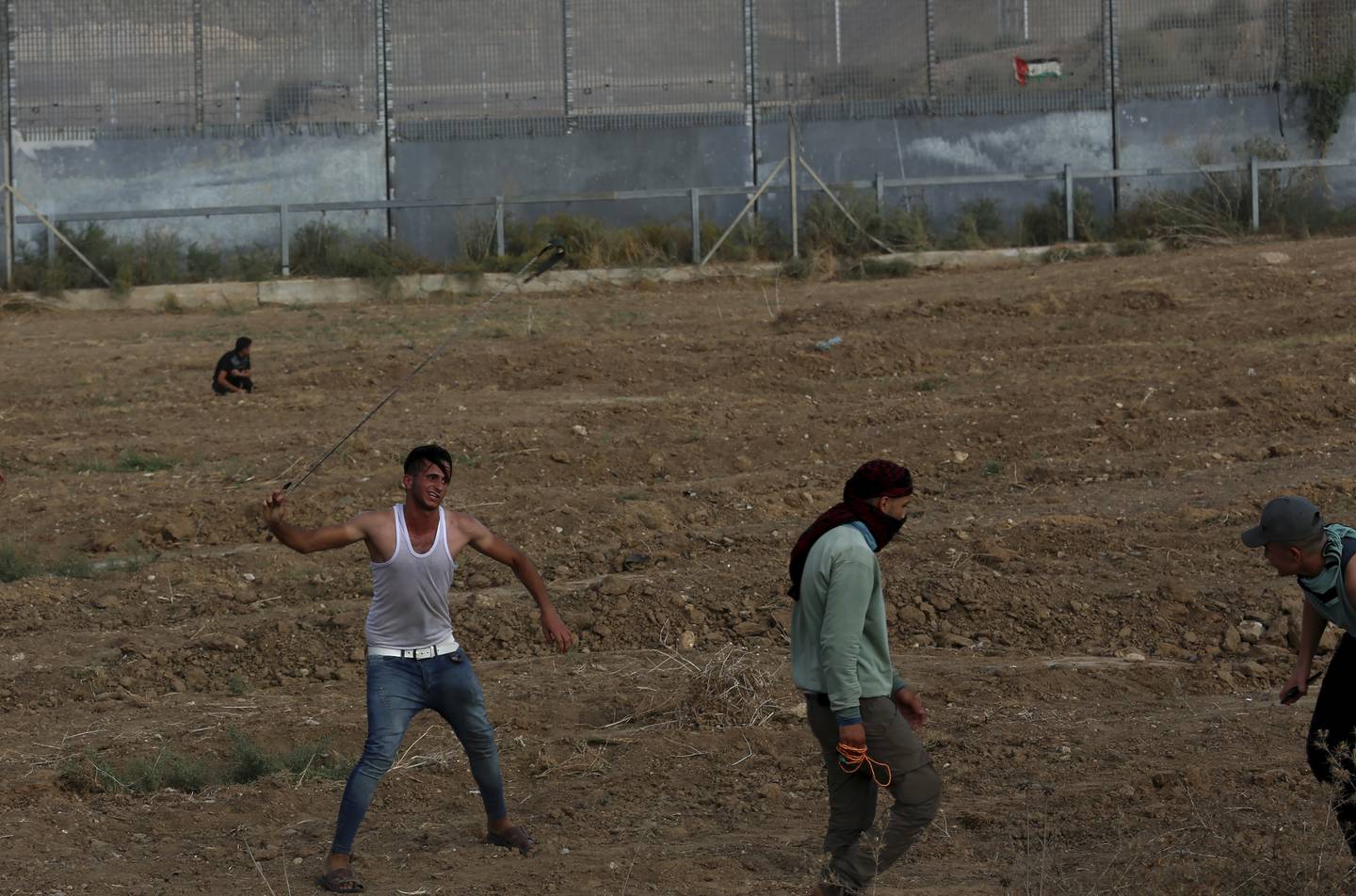 Men hurl stones at Israeli troops near the border fence between the Gaza Strip and Israel during a protest marking the anniversary of a 1969 arson attack at Al Aqsa Mosque in Jerusalem. AP