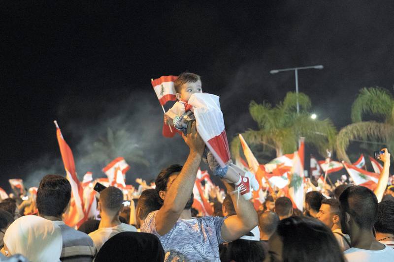 A man holds a baby wrapped in the Lebanese flag high in the air during a protest in Sour. William Lowry / The National