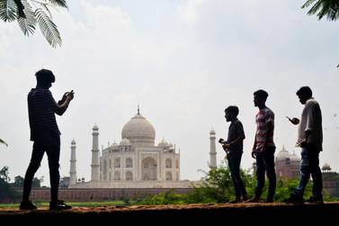 People take pictures with their phones near the Taj Mahal, which will reopen later this month. AFP