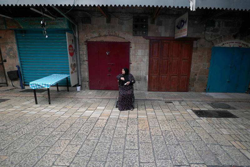 A Palestinian woman sits in front of shuttered stores in the northern Israeli city of Acre. AFP