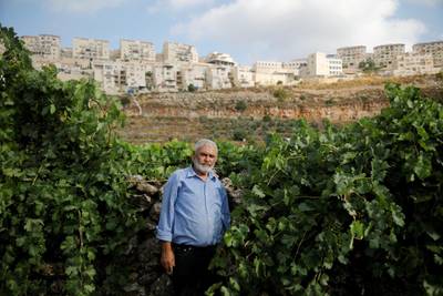 FILE PHOTO: Palestinian man Mohammad Awad, 64, poses for a photo at his farm in the village of Wadi Fukin with the Jewish settlement of Beitar Illit in the background, in the Israeli-occupied West Bank, July 21, 2019. "It's impossible to have peace between us because the main conflict between us is on a piece of land which they took by force, so how can I let a person steal my land, live in it and enjoy it, and live with him in peace?" he said. REUTERS/Raneen Sawafta/File Photo