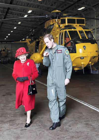 HOLYHEAD, UNITED KINGDOM - APRIL 01:  Queen Elizabeth II is escorted by her grandson Prince William during a visit to RAF Valley where Prince William is stationed as a search and rescue helicopter pilot on April 1, 2011 in Holyhead, United Kingdom. The Queen toured the airbase meeting staff and families, watched a fly past and was given a guided tour of a Sea King search and rescue helicopter by Prince William.  (Photo by Christopher Furlong-WPA-Pool/Getty Images)