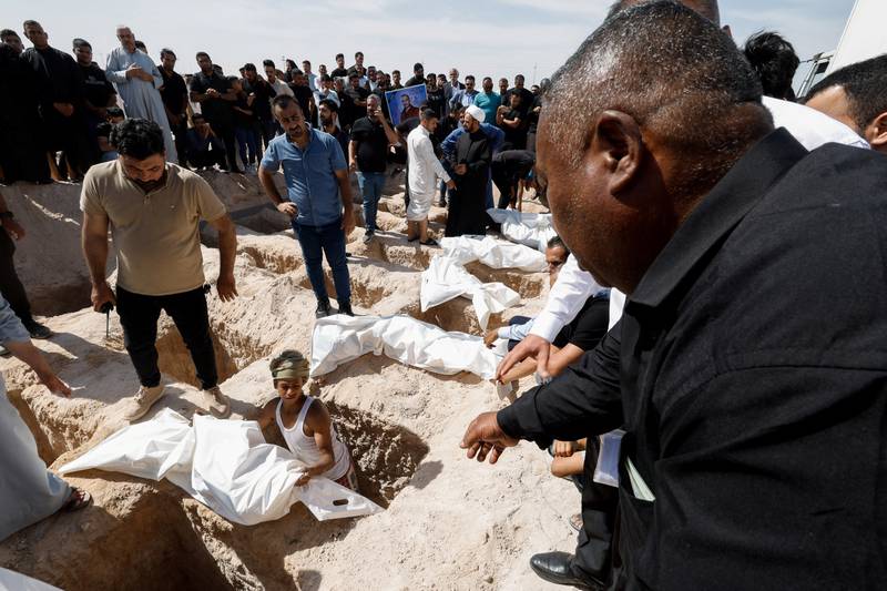Iraqi men bury the remains of some of those exhumed from mass graves, in Najaf. Reuters