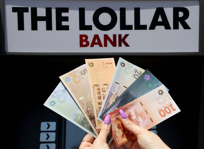 A Lebanese activist displays fake banknotes called “Lollars”, in front of a mock ATM, during a stunt to denounce the high-level of corruption that has wrecked the country. AFP