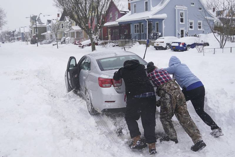 Neighbours push a motorist stuck in the snow in the Buffalo region. AP