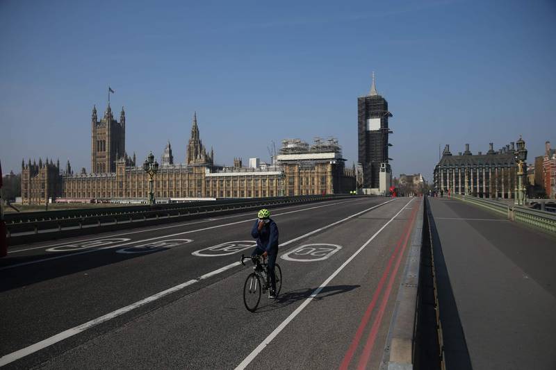 A cyclist crosses a near-empty Westminster Bridge with the Houses of Parliament in the background in central London.  AFP