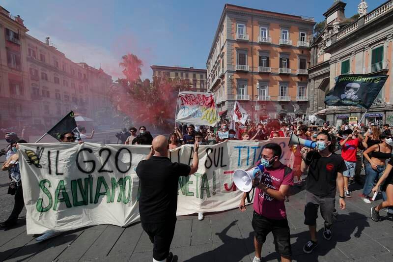 People hold a banner reading in Italian 'The G20 dances on Titanic, let's Save the planet, go away!'.