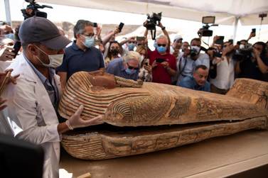 An archaeology worker opens a sarcophagus at the Saqqara archaeological site, 30 kilometers (19 miles) south of Cairo, Egypt, on Saturday, Oct. 3, 2020, in the presence of journalists and officials. Egypt’s ministry of antiquities and tourism says at least 59 sealed sarcophagi with mummies inside were found that had been buried in three wells more than 2,600 years ago. (AP Photo/Mahmoud Khaled)